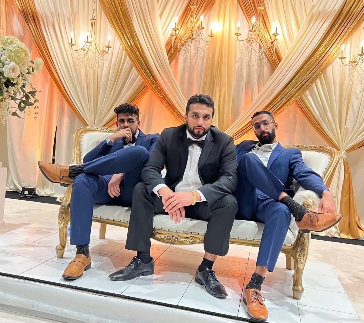 DJ Taj Productions team posed at wedding venue with gold drapes